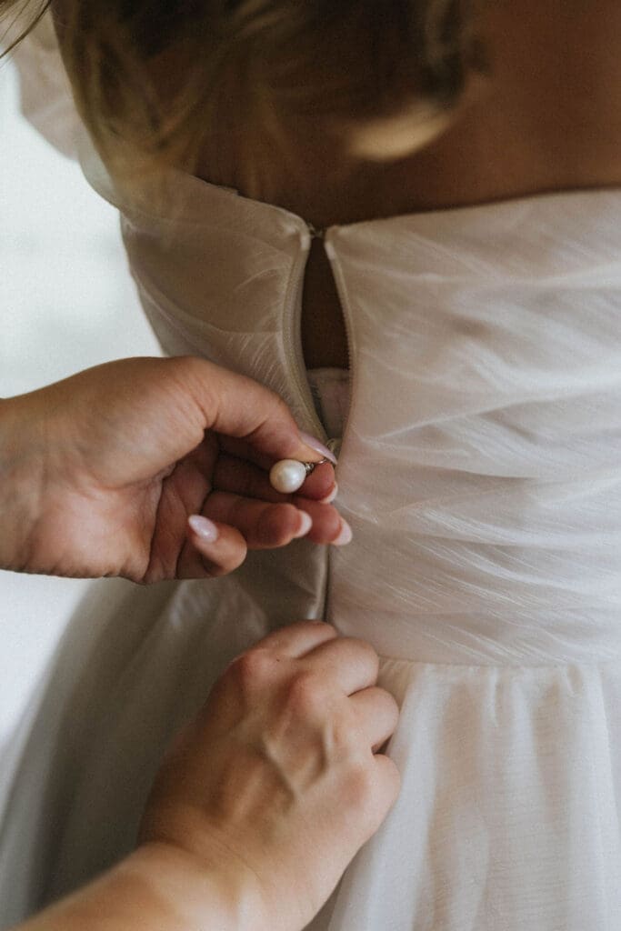 Bride getting ready and being buttoned into her wedding dress before an elegant estate wedding in Washington, photographed by Seattle wedding photographer Valen Lee Photography.
