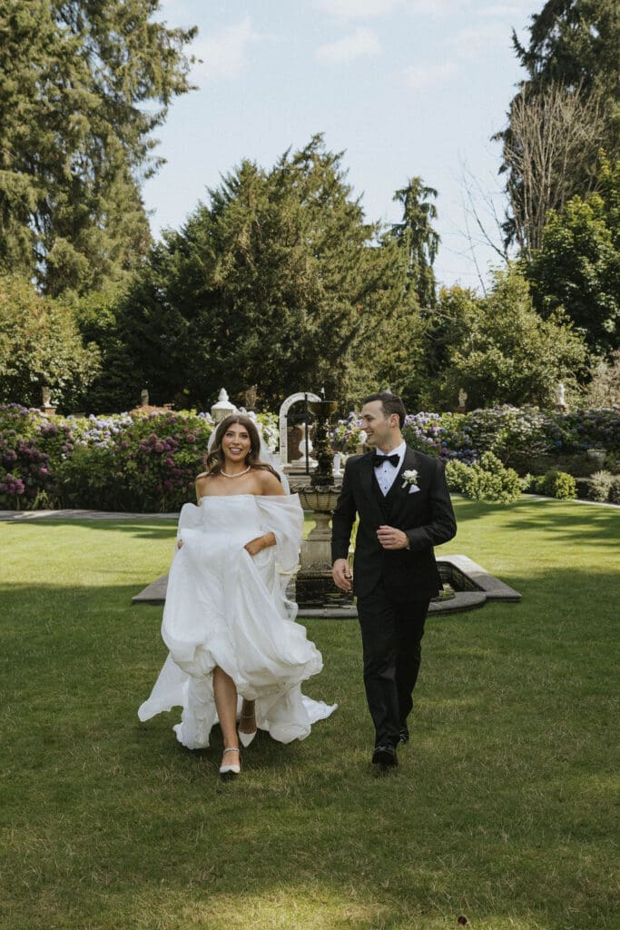 Bride and groom smiling and running toward the camera with her flowy dress, photographed by Seattle wedding photographer Valen Lee Photography.