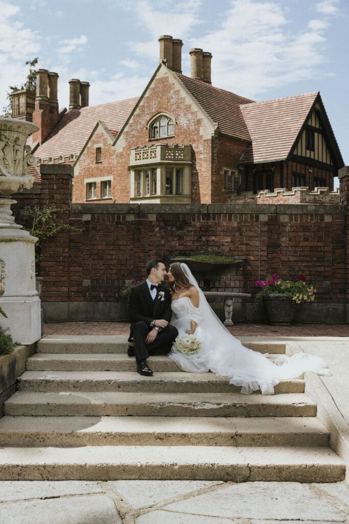 bride and groom sitting on stairs with brick castle behind them in a romantic pose, photographed by Seattle wedding photographer Valen Lee Photography.