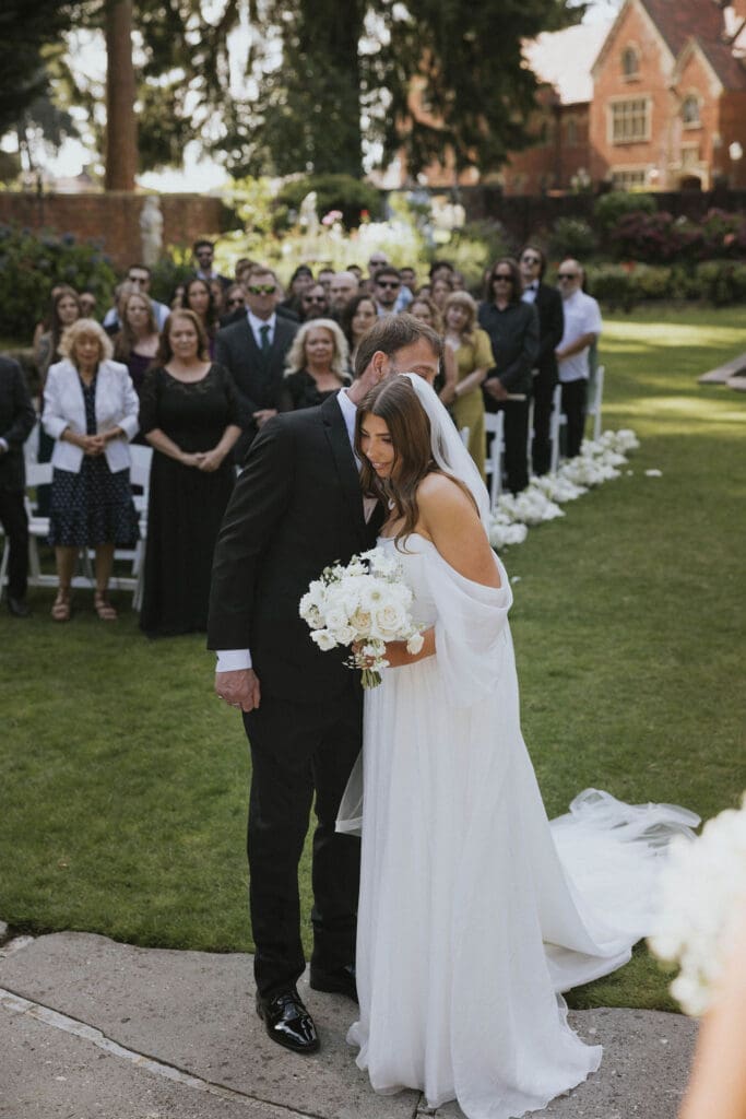 Bride walking down the aisle with her father during an elegant outdoor garden wedding ceremony in Washington.