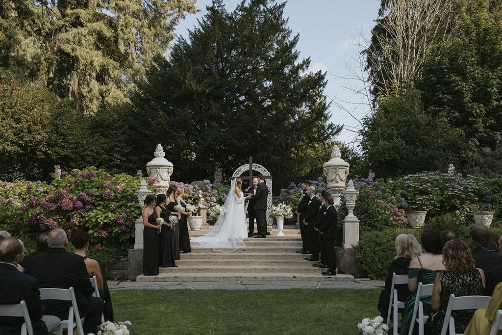 Bride and groom exchanging vows during an outdoor garden wedding ceremony at a historic Washington estate.