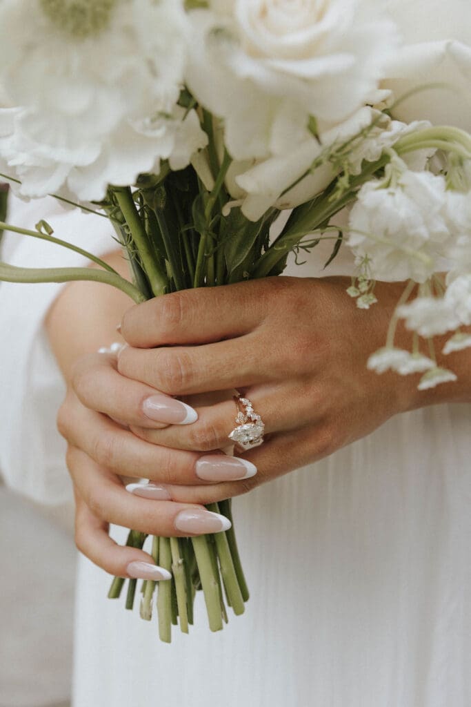 Close-up of bride holding a white floral bouquet and showing her engagement ring during her Washington wedding.