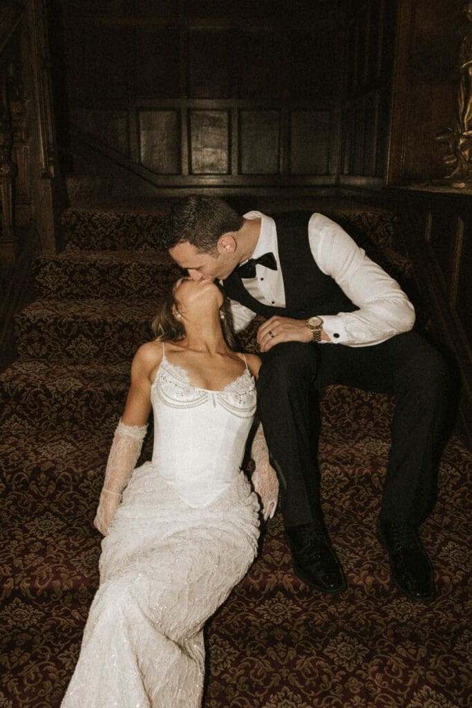 Bride and groom sharing a romantic kiss on a grand staircase inside a historic Washington wedding venue.