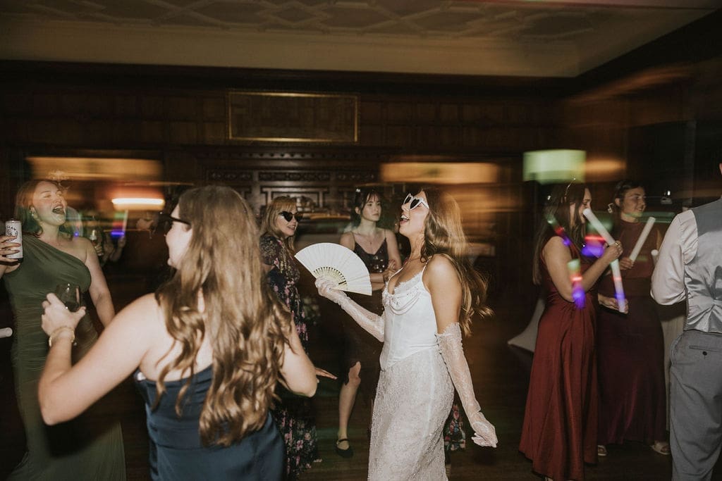 Bride dancing with wedding guests during a lively indoor reception in a ballroom at a historic Washington estate wedding venue.